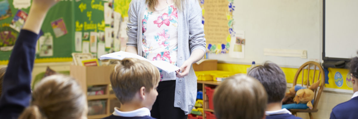 White female teacher standing in front of primary pupils